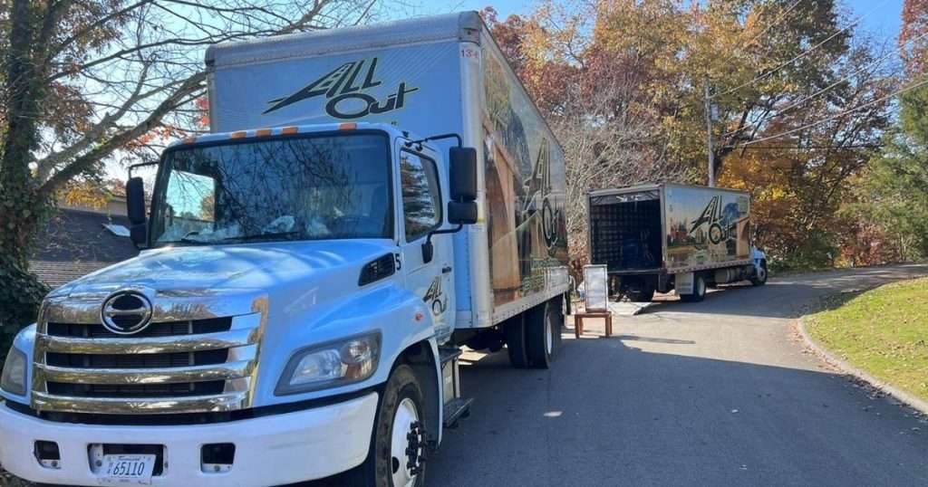Two All Out Moving & Storage branded moving trucks parked at the curb in front of a home with the ramps down as Chattanooga movers load belongings during a residential move